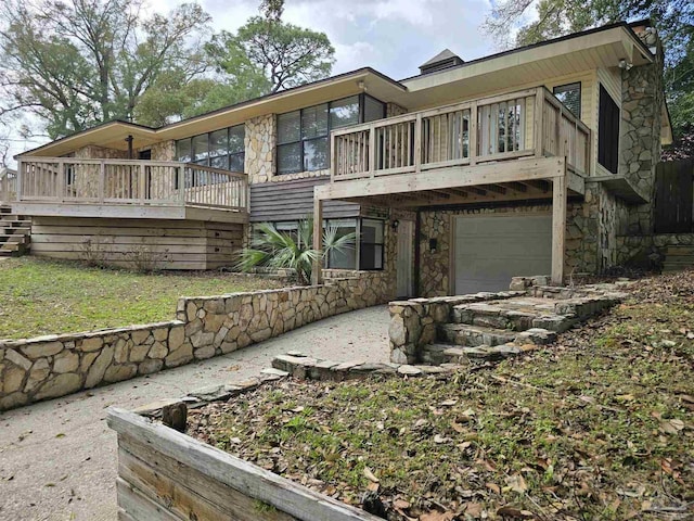 view of front of property with stone siding, a wooden deck, and an attached garage