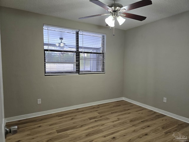 spare room with a textured ceiling, ceiling fan, wood finished floors, and baseboards