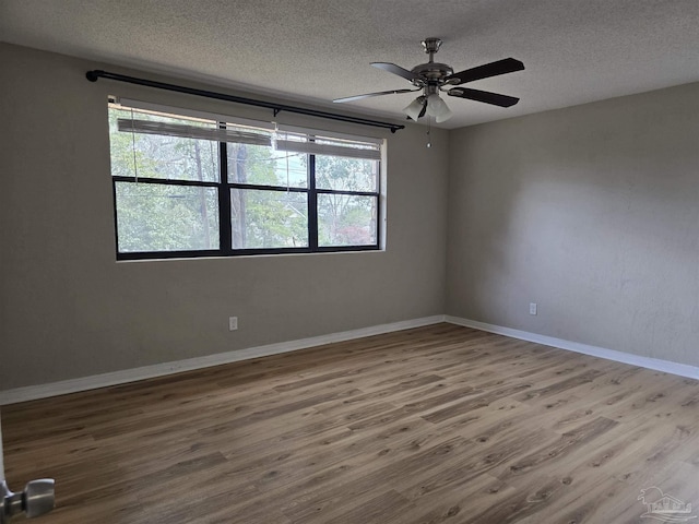 unfurnished room with a ceiling fan, a textured ceiling, baseboards, and wood finished floors