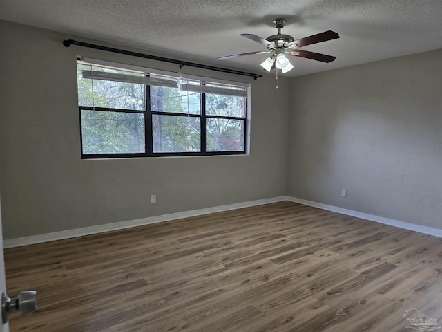 spare room featuring ceiling fan, a textured ceiling, baseboards, and wood finished floors