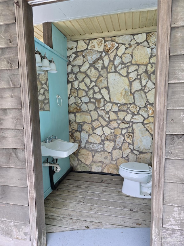 half bathroom featuring wood ceiling, a sink, toilet, and wood finished floors