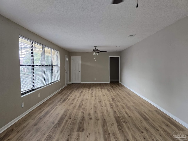 unfurnished living room with baseboards, wood finished floors, visible vents, and a ceiling fan