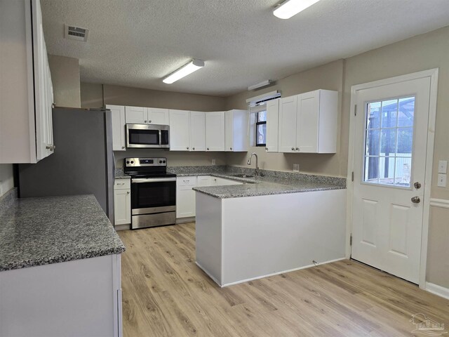 kitchen featuring visible vents, stainless steel appliances, light wood-type flooring, white cabinetry, and a sink