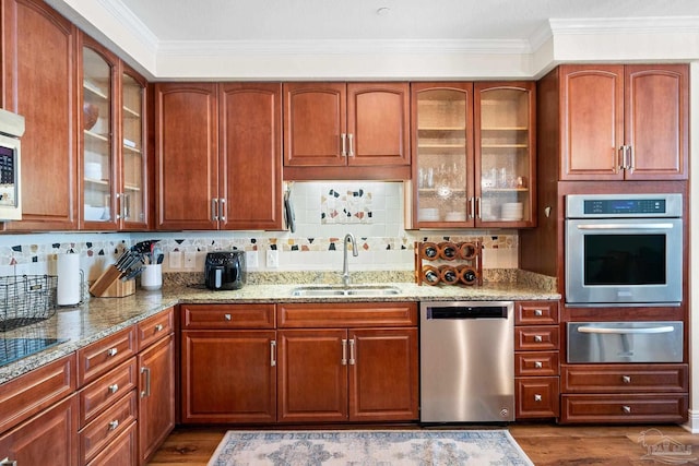 kitchen featuring light stone counters, ornamental molding, stainless steel appliances, and sink