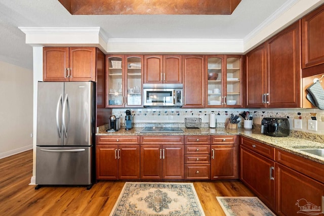 kitchen featuring crown molding, light hardwood / wood-style flooring, appliances with stainless steel finishes, light stone counters, and decorative backsplash