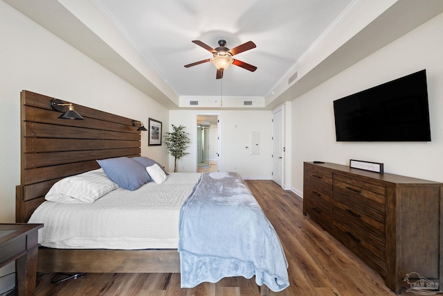 bedroom featuring crown molding, ceiling fan, a tray ceiling, and dark hardwood / wood-style flooring