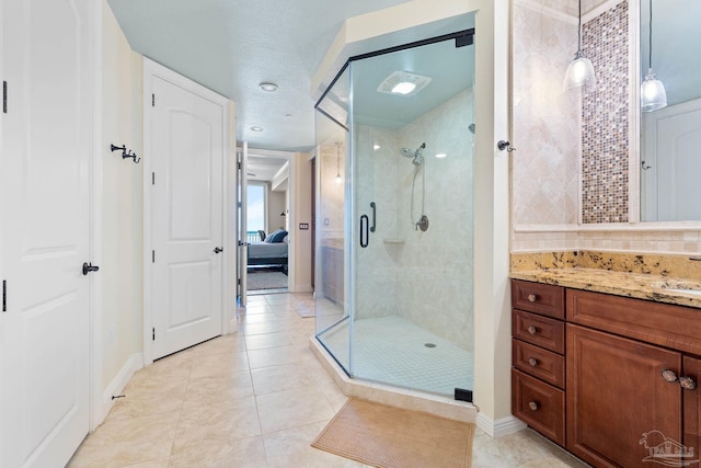 bathroom featuring tile patterned flooring, vanity, tasteful backsplash, and walk in shower