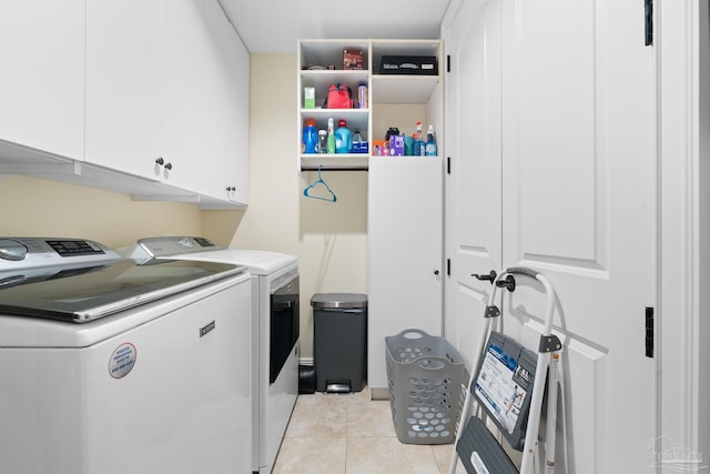 laundry room with cabinets, light tile patterned floors, and washing machine and clothes dryer