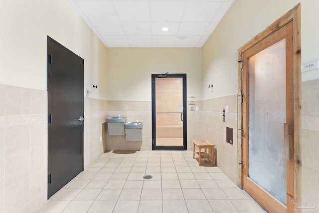 bathroom with tile walls, a paneled ceiling, and tile patterned floors