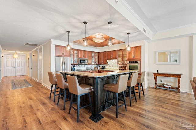 kitchen with stainless steel appliances, light stone countertops, light wood-type flooring, and decorative light fixtures