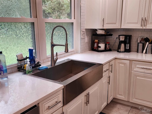 kitchen with sink, light stone countertops, light tile patterned floors, and tasteful backsplash