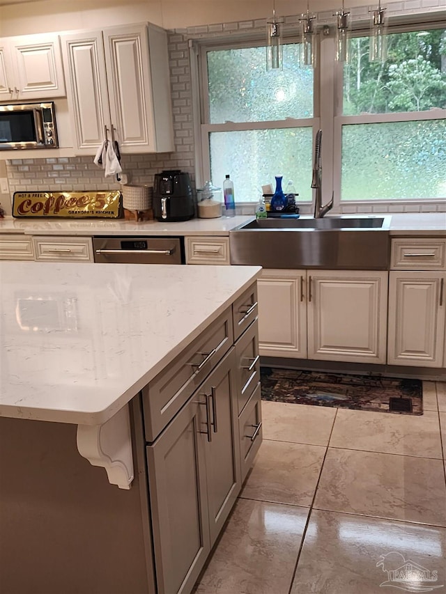 kitchen featuring tasteful backsplash, appliances with stainless steel finishes, white cabinetry, light tile patterned flooring, and sink