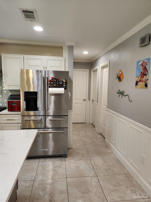 kitchen featuring stainless steel fridge, crown molding, white cabinetry, light stone counters, and tasteful backsplash