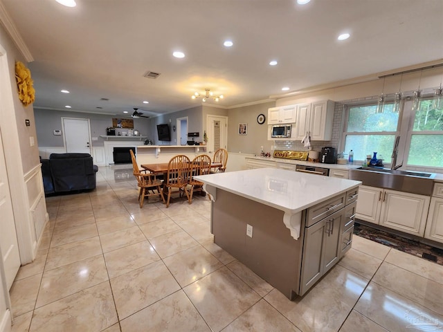 kitchen with white cabinets, a center island, stainless steel appliances, and ceiling fan