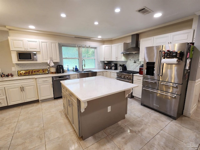 kitchen with appliances with stainless steel finishes, sink, a center island, wall chimney exhaust hood, and white cabinets