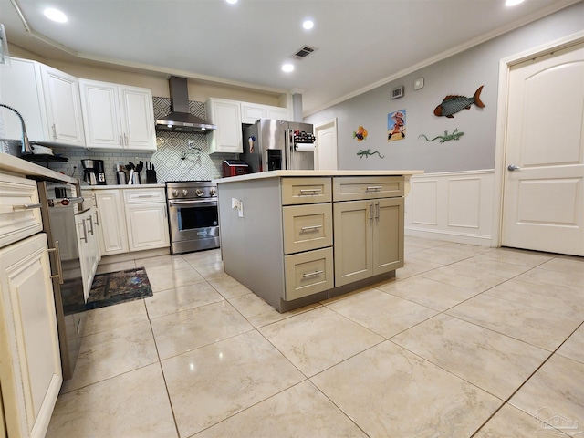 kitchen featuring a kitchen island, appliances with stainless steel finishes, wall chimney range hood, and white cabinetry