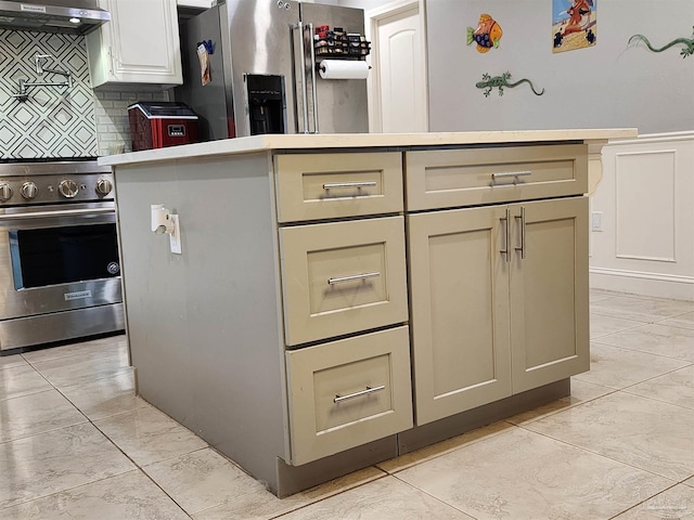 kitchen with cream cabinets, stainless steel appliances, exhaust hood, and backsplash