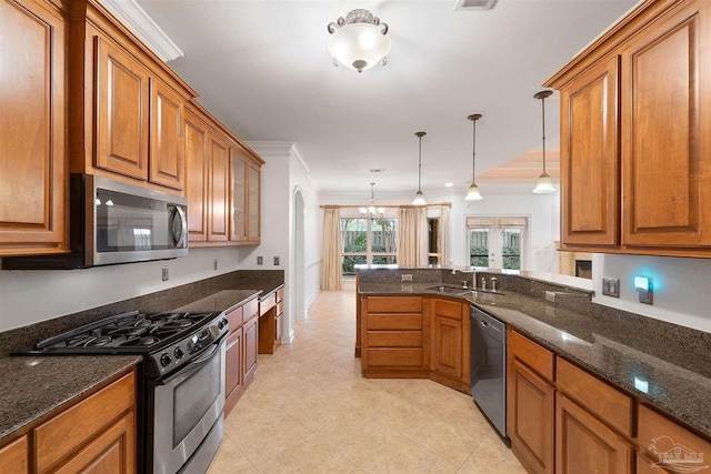 kitchen featuring hanging light fixtures, dark stone counters, ornamental molding, sink, and stainless steel appliances