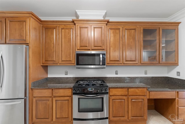 kitchen with crown molding, stainless steel appliances, and dark stone counters