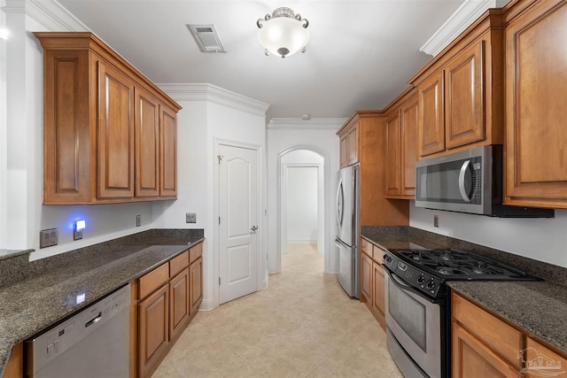 kitchen featuring appliances with stainless steel finishes, crown molding, and dark stone countertops