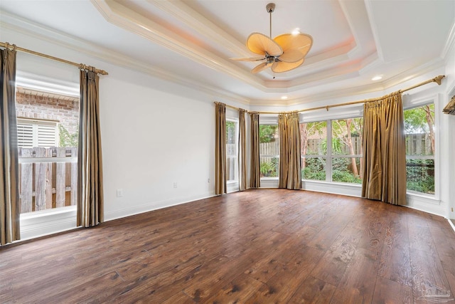 unfurnished room featuring dark wood-type flooring, ornamental molding, a healthy amount of sunlight, and a tray ceiling