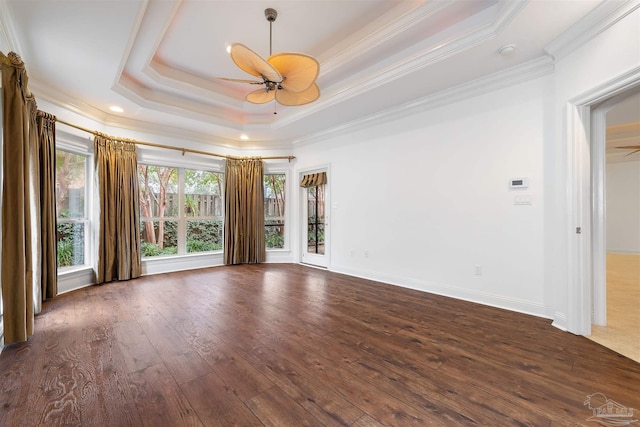 spare room with dark wood-type flooring, ceiling fan, a raised ceiling, and ornamental molding