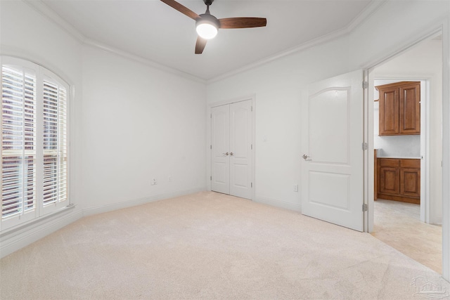 unfurnished bedroom with crown molding, light carpet, a closet, and ceiling fan