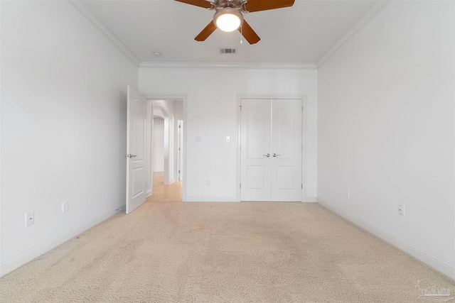 unfurnished bedroom featuring light carpet, a closet, ornamental molding, and ceiling fan