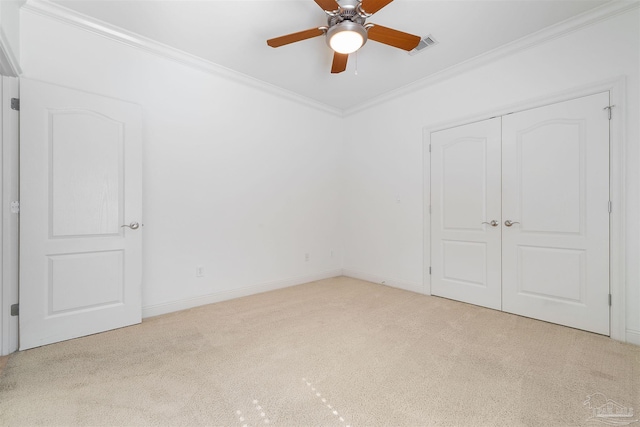 unfurnished bedroom with light carpet, crown molding, a closet, and ceiling fan