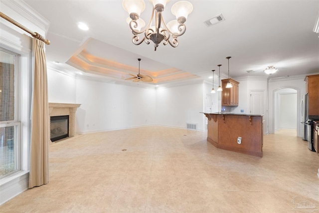 unfurnished living room with a raised ceiling, ornamental molding, ceiling fan with notable chandelier, and a premium fireplace