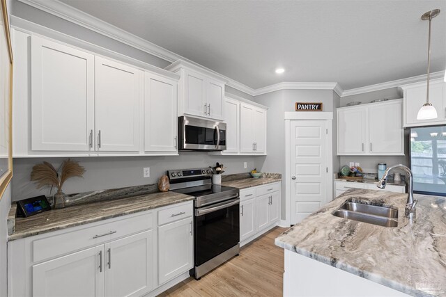1223 Fenwick Ct, Cantonment, FL 32533 - kitchen featuring appliances with stainless steel finishes, white cabinetry, ornamental molding, light wood-style flooring, and hanging light fixtures
