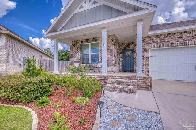 1223 Fenwick Ct, Cantonment, FL 32533 - view of exterior entry with covered porch, brick siding, a garage, concrete driveway, and board and batten siding