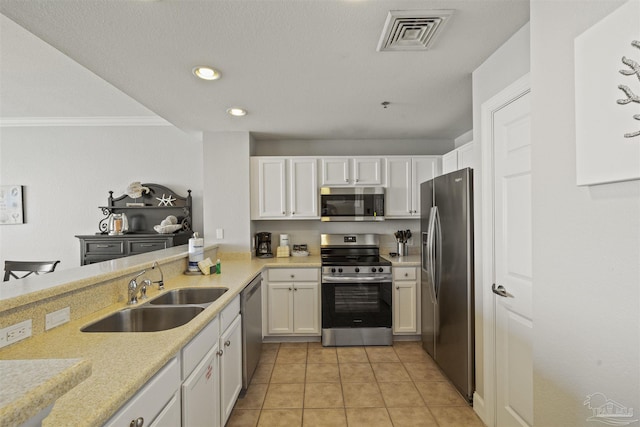 kitchen with light tile patterned floors, white cabinetry, appliances with stainless steel finishes, ornamental molding, and sink