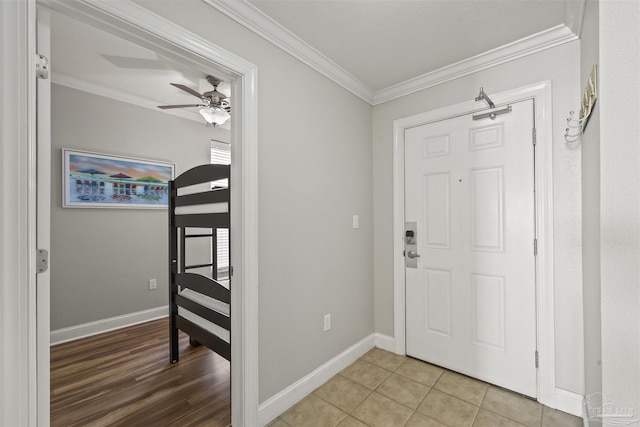 tiled entrance foyer with ceiling fan and ornamental molding