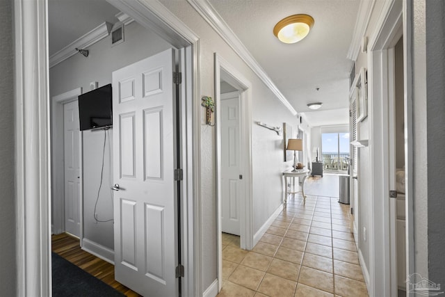 hallway featuring light tile patterned floors and crown molding