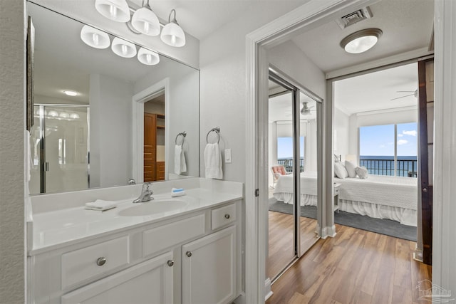 bathroom with hardwood / wood-style floors, vanity, walk in shower, a water view, and ceiling fan