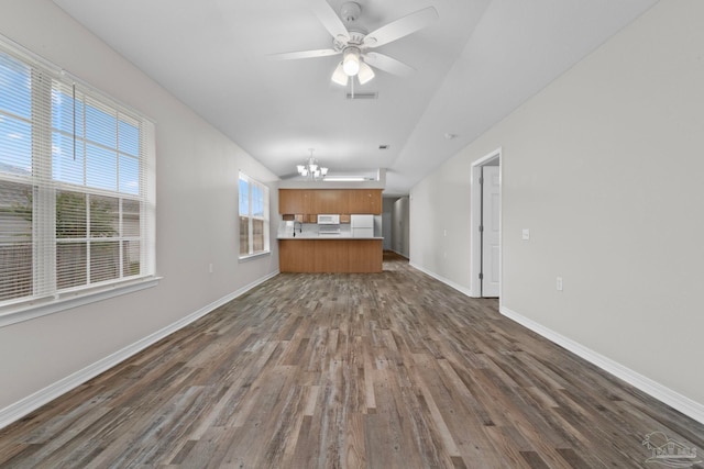 unfurnished living room featuring ceiling fan with notable chandelier and dark hardwood / wood-style flooring