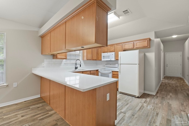 kitchen featuring white appliances, kitchen peninsula, light hardwood / wood-style floors, and sink