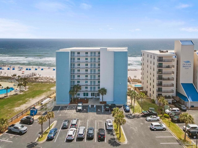 view of property featuring a beach view, uncovered parking, and a water view