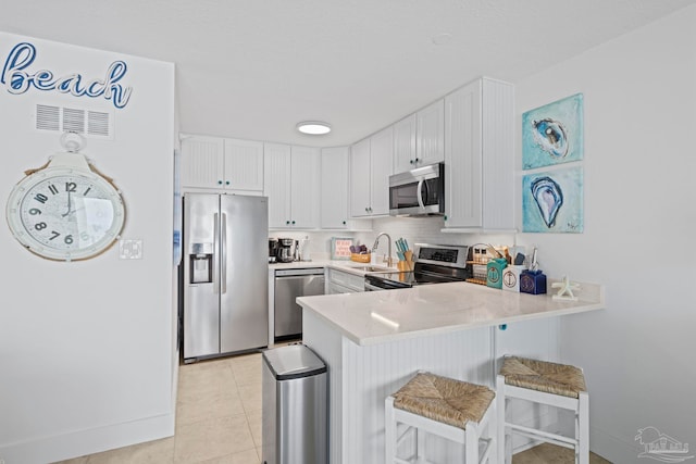 kitchen featuring light countertops, a sink, a breakfast bar area, a peninsula, and stainless steel appliances