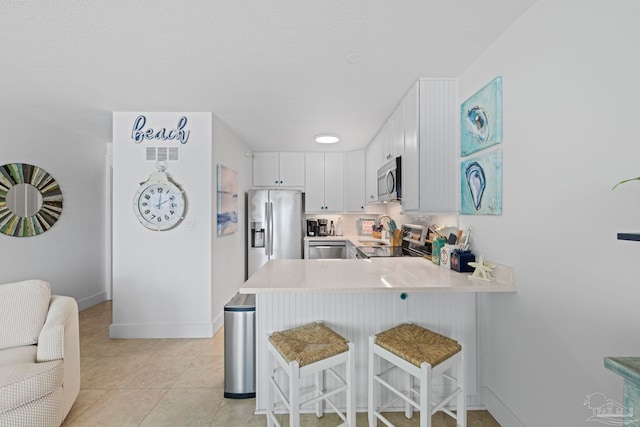 kitchen featuring a kitchen breakfast bar, light countertops, stainless steel appliances, visible vents, and a peninsula