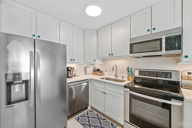 kitchen with white cabinetry, light countertops, tasteful backsplash, stainless steel appliances, and a sink