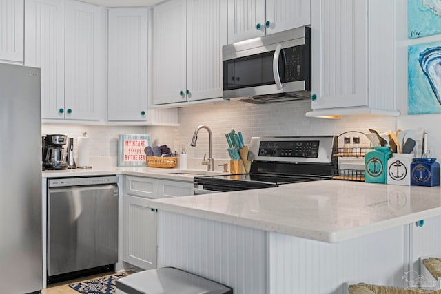 kitchen featuring a sink, backsplash, appliances with stainless steel finishes, and light stone counters