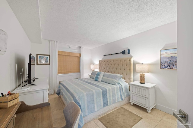 bedroom with light tile patterned floors, baseboards, and a textured ceiling