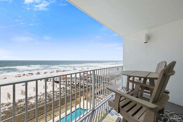 balcony with a water view and a view of the beach