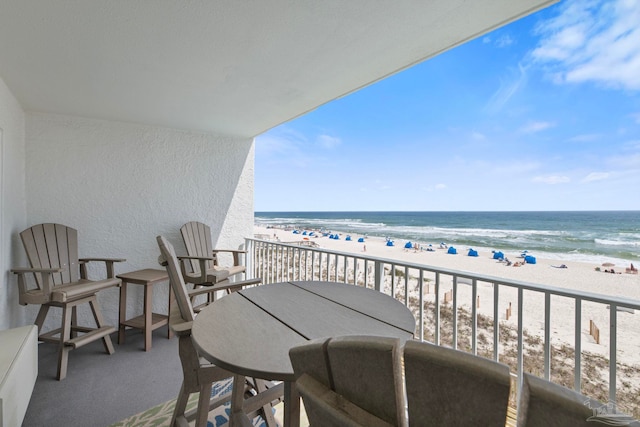 balcony with a water view and a view of the beach