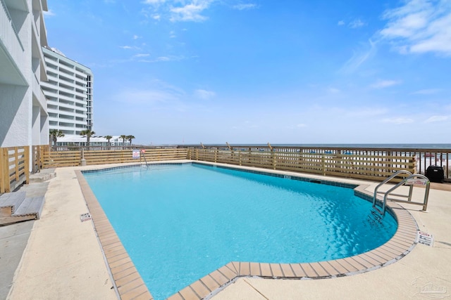 community pool featuring a water view, fence, and a patio