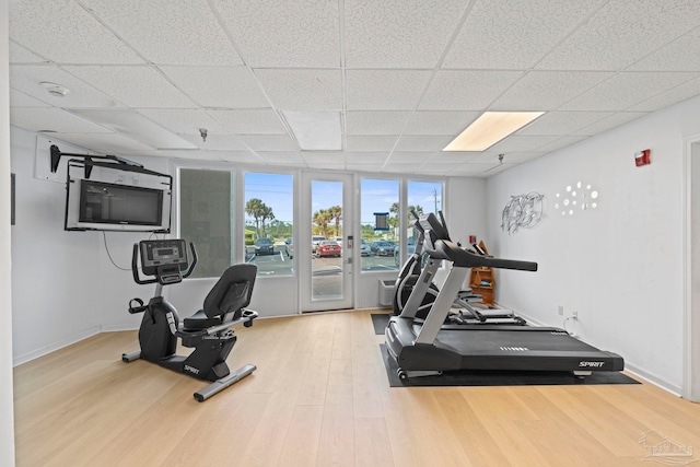 workout room featuring baseboards, wood finished floors, and a paneled ceiling