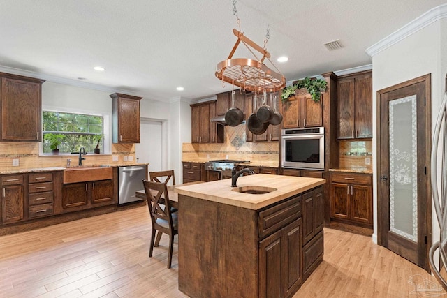 6781 Generals Ln, Pace, FL 32571 - kitchen with appliances with stainless steel finishes, backsplash, wood counters, ornamental molding, and an island with sink