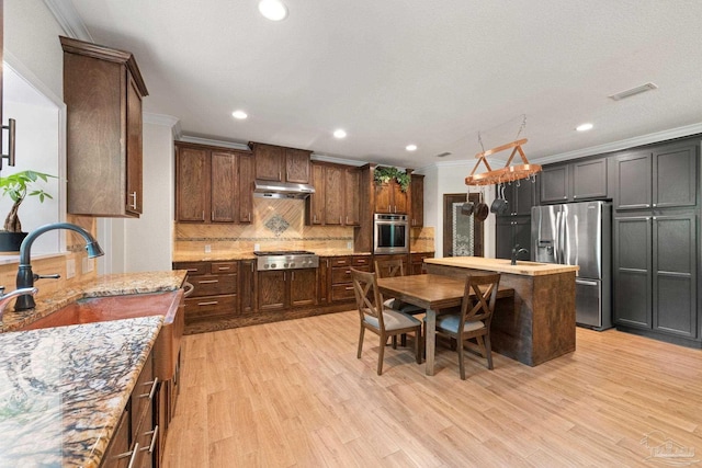 6781 Generals Ln, Pace, FL 32571 - kitchen with appliances with stainless steel finishes, under cabinet range hood, ornamental molding, decorative backsplash, and light wood-style flooring